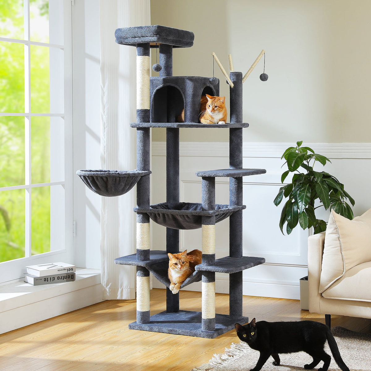 Dunkelgrauer Mid-Rise Kratzbaum in einem hellen Wohnzimmer, drei Katzen verteilen sich auf Hängematten und Plattformen