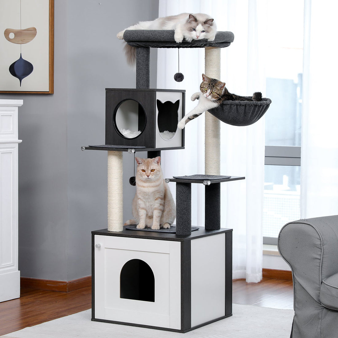 Schwarz-weißer Katzenbaum mit dicken Sisalstämmen, großer Liegefläche und drei Katzen in einem hellen Wohnzimmer