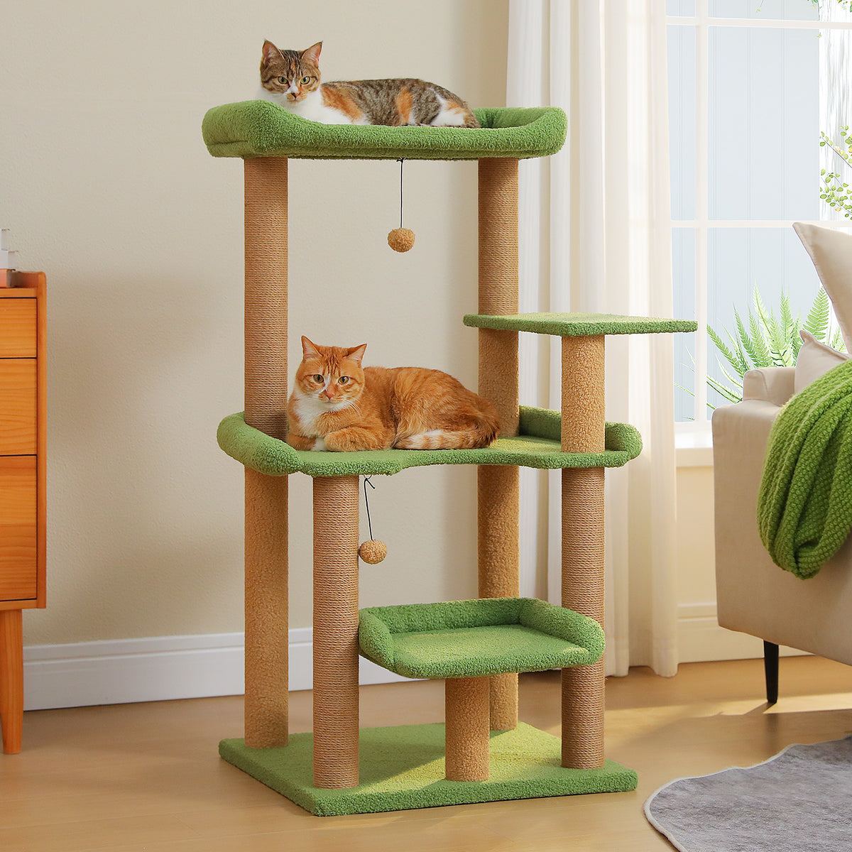 Forest green 110cm cat tree with hanging ball toys, calico cat on the top perch and orange tabby below