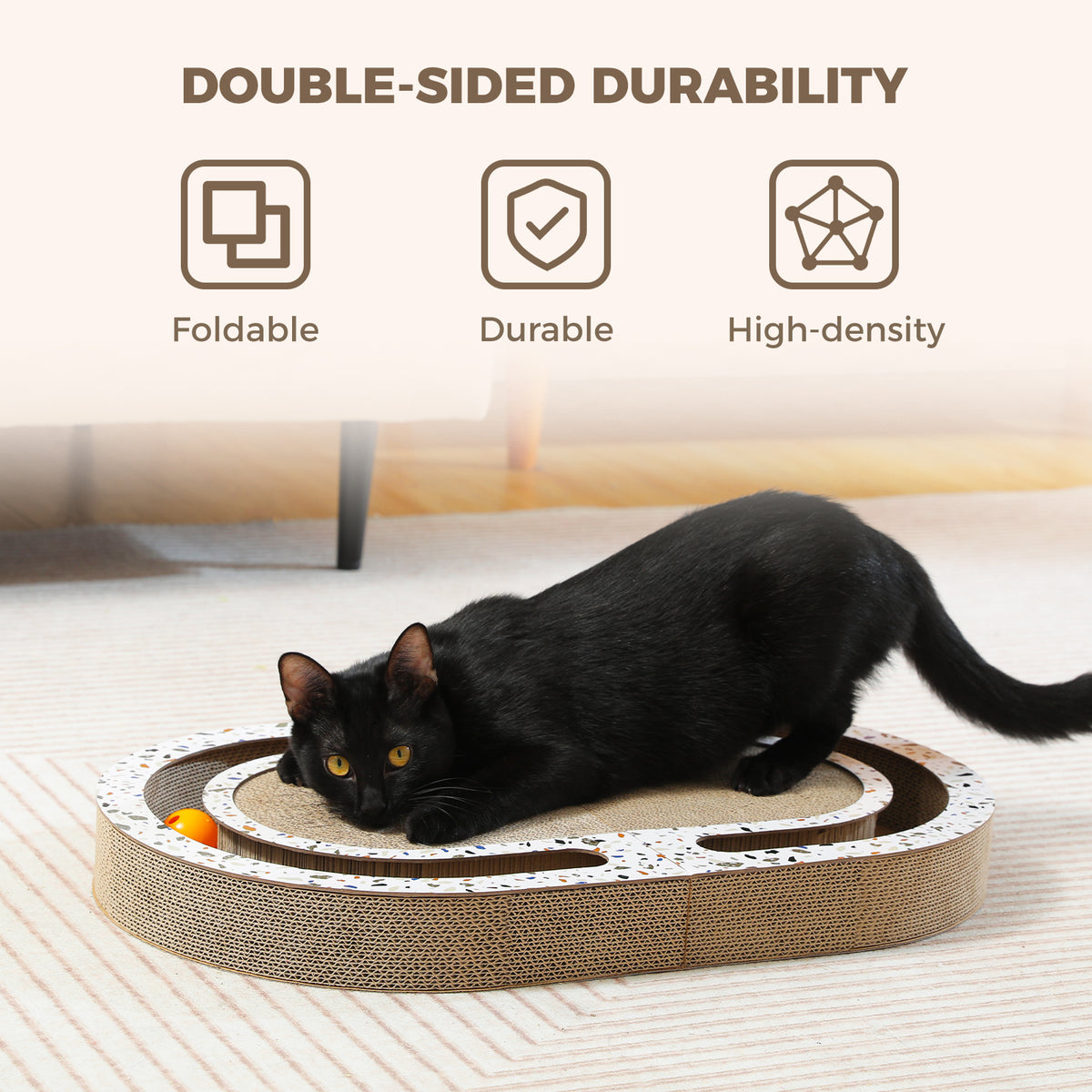 Black cat crouched on the cardboard scratcher pawing an orange track ball beneath a Double-Sided Durability banner