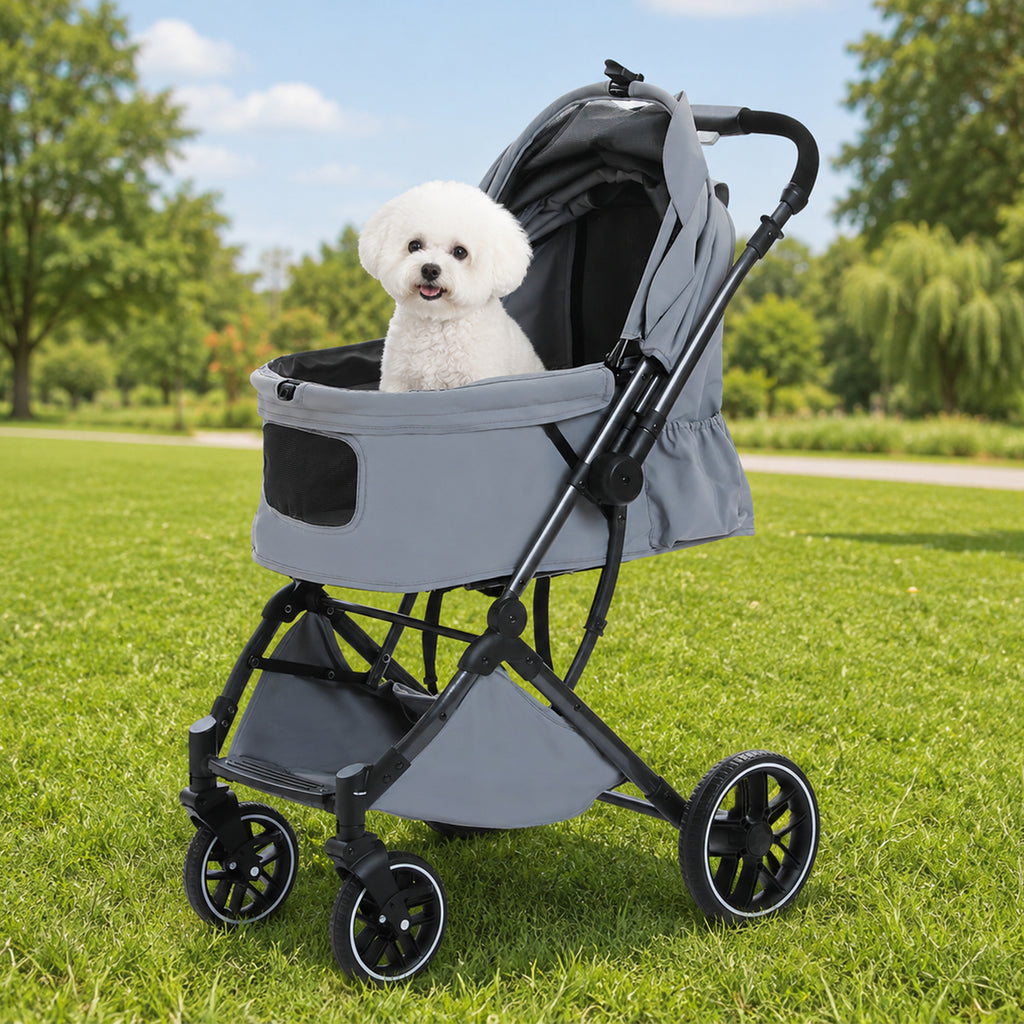 Grey pet stroller with a fluffy white dog inside parked on a sunny lawn, canopy half-open over the mesh window